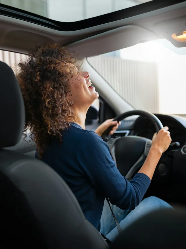 Mulher ao volante de um veículo, em um ambiente real